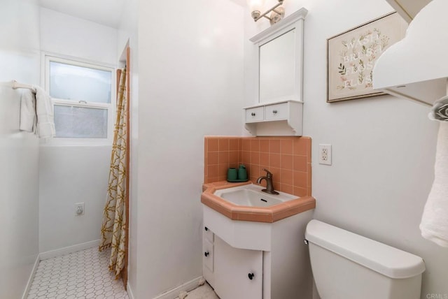 full bathroom featuring curtained shower, toilet, vanity, baseboards, and tasteful backsplash