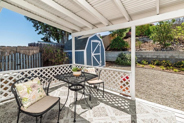 view of patio featuring a storage unit, an outbuilding, and fence