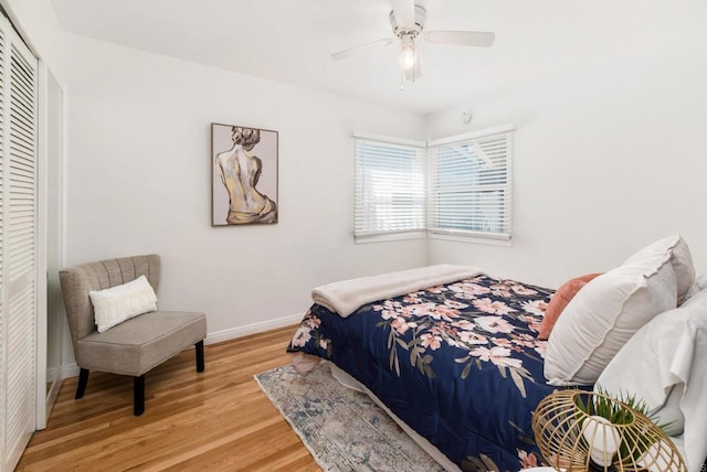 bedroom featuring baseboards, wood finished floors, a closet, and a ceiling fan