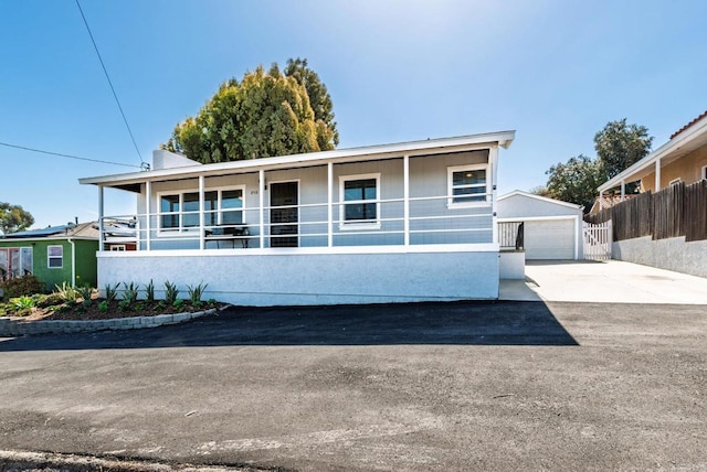 view of front of home with stucco siding, fence, an outdoor structure, a garage, and a porch