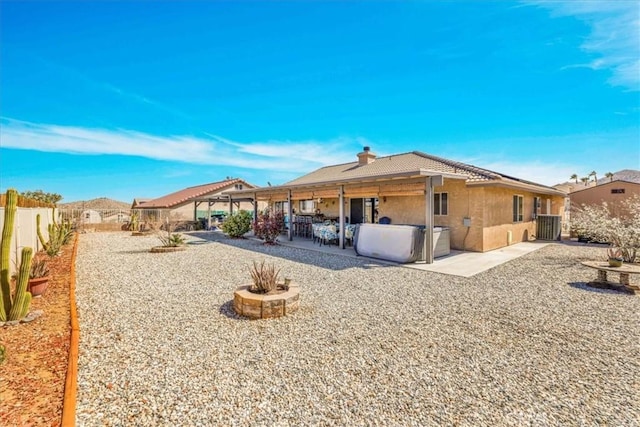 back of house featuring a chimney, stucco siding, a patio area, fence, and a jacuzzi