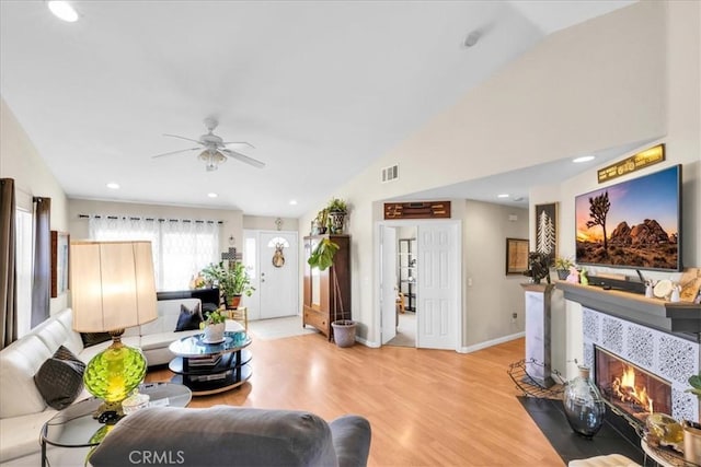 living room featuring lofted ceiling, a premium fireplace, and light wood-type flooring