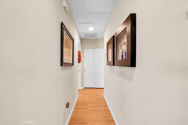 corridor with visible vents, light wood-style floors, attic access, and baseboards