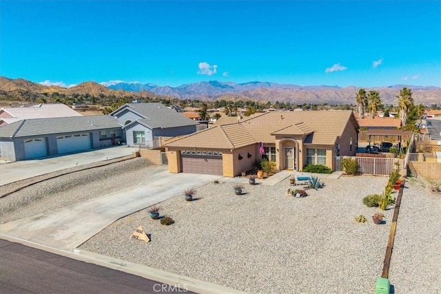 ranch-style home featuring driveway, a tiled roof, an attached garage, fence, and a mountain view