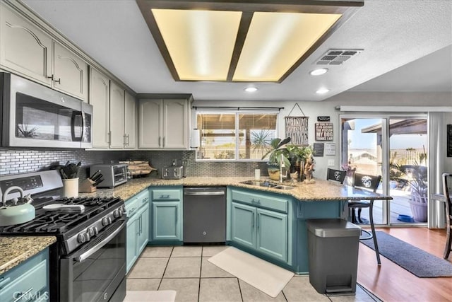 kitchen featuring stainless steel appliances, visible vents, a sink, and backsplash