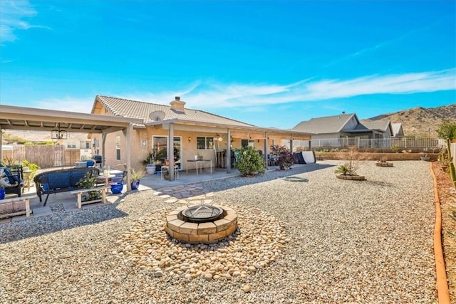 back of property featuring a fire pit, a fenced backyard, a chimney, a tiled roof, and a patio area