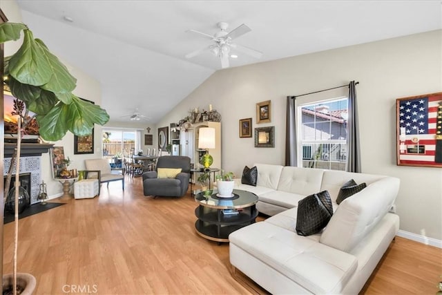 living room featuring ceiling fan, lofted ceiling, a tile fireplace, wood finished floors, and baseboards