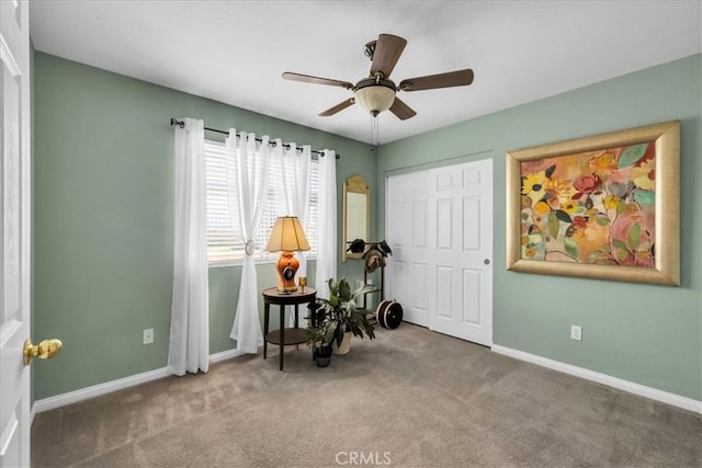 living area featuring carpet, baseboards, and ceiling fan