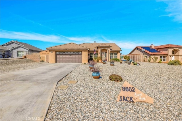 view of front facade with a garage, a tile roof, fence, driveway, and stucco siding