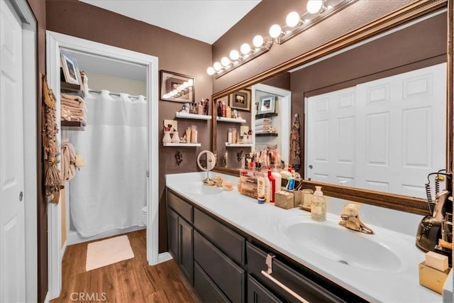 bathroom with double vanity, wood finished floors, a sink, and toilet