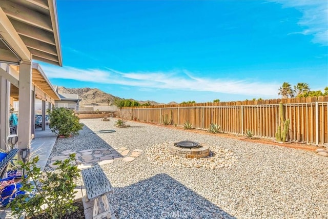 view of yard featuring an outdoor fire pit, a mountain view, a fenced backyard, and a patio