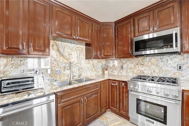 kitchen with a toaster, light stone counters, stainless steel appliances, and a sink