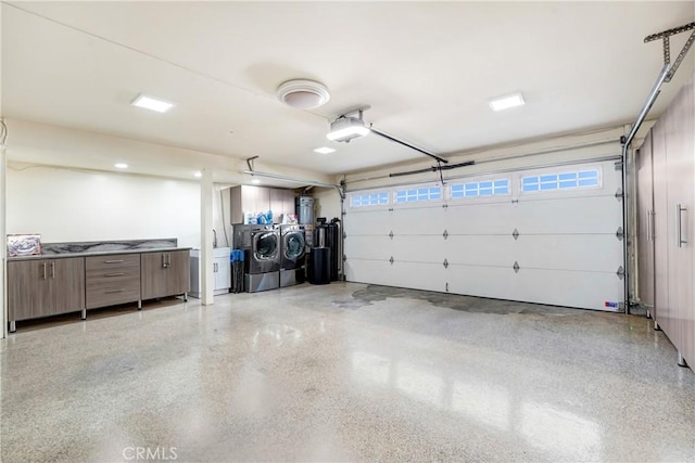 garage featuring strapped water heater, washer and dryer, and a garage door opener