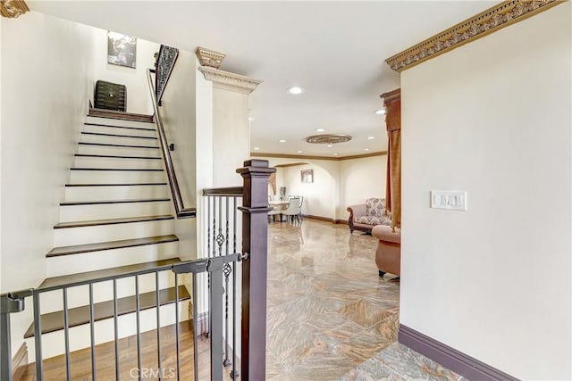 staircase with baseboards, arched walkways, ornamental molding, and recessed lighting