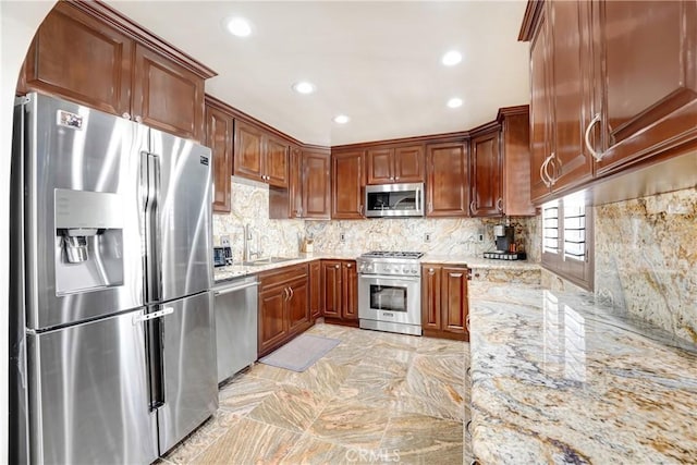 kitchen with recessed lighting, a sink, appliances with stainless steel finishes, light stone countertops, and tasteful backsplash