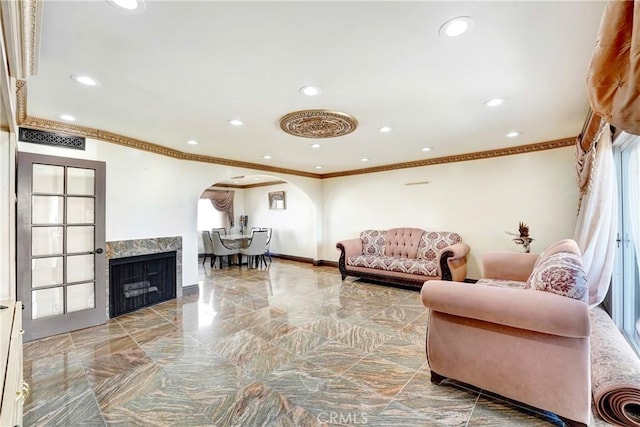 living area with baseboards, arched walkways, crown molding, a fireplace, and recessed lighting