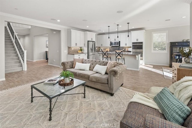 living room with light wood-type flooring, crown molding, recessed lighting, and stairs