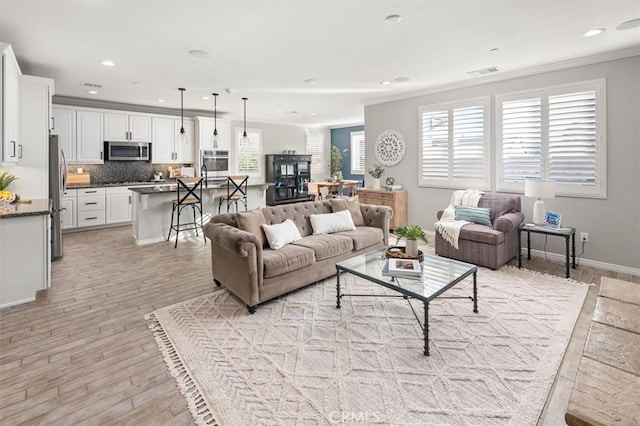 living area featuring crown molding, recessed lighting, visible vents, light wood-style flooring, and baseboards