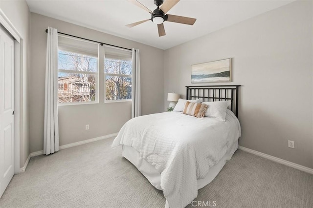 bedroom with a ceiling fan, a closet, light colored carpet, and baseboards