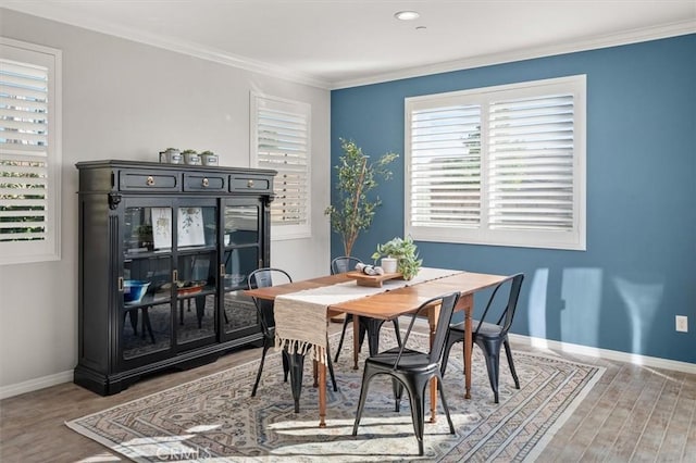 dining area featuring crown molding, baseboards, and wood finished floors