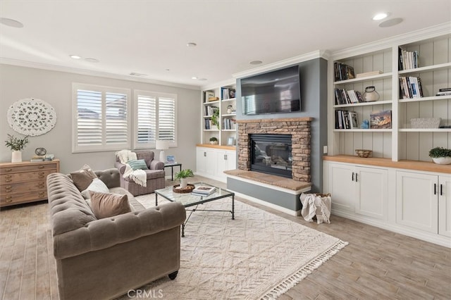 living area featuring a stone fireplace, light wood-style flooring, recessed lighting, visible vents, and ornamental molding