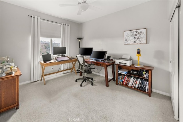 carpeted office space featuring ceiling fan and baseboards