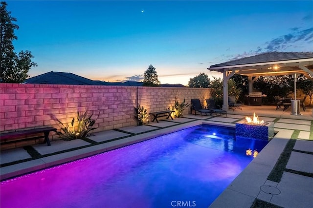 pool at dusk featuring a patio, an outdoor fire pit, fence private yard, a gazebo, and a fenced in pool