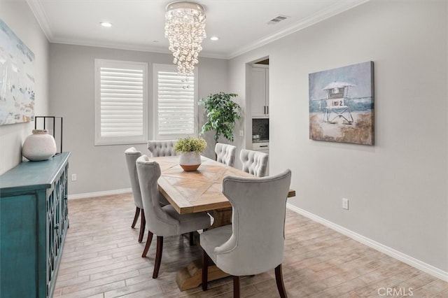 dining room featuring light wood-style flooring, crown molding, visible vents, and a notable chandelier