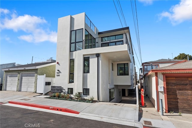 view of front of house featuring a garage, a balcony, and stucco siding