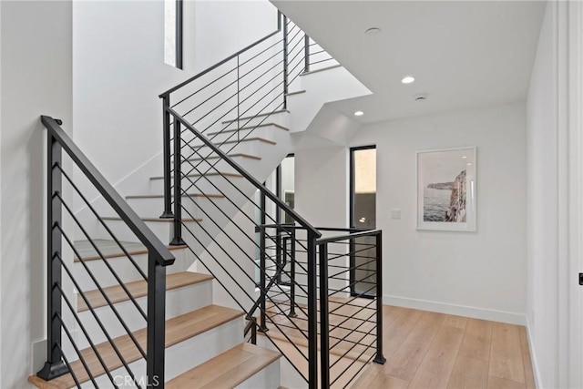 stairway featuring baseboards, wood finished floors, and recessed lighting