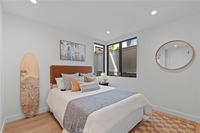 bedroom featuring baseboards, wood finished floors, and recessed lighting