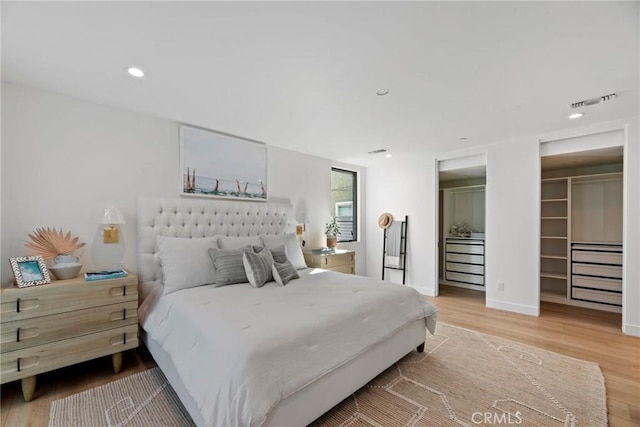 bedroom with recessed lighting, wood finished floors, visible vents, baseboards, and a spacious closet