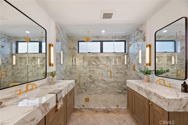 bathroom with a marble finish shower, visible vents, and a sink