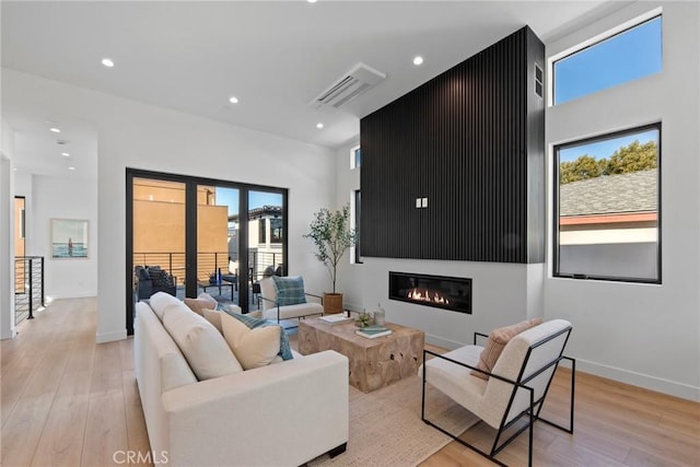 living room featuring light wood-type flooring, baseboards, visible vents, and recessed lighting