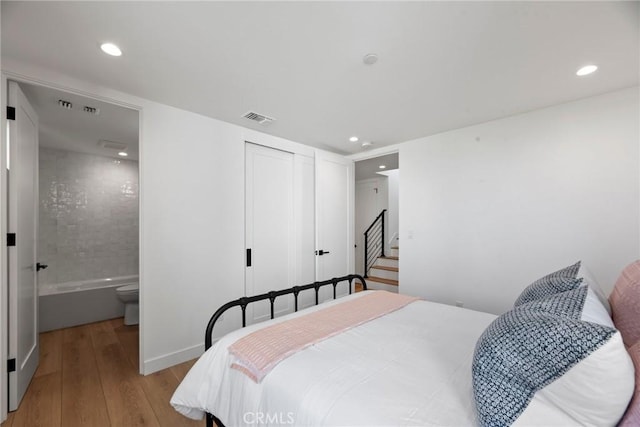 bedroom with recessed lighting, visible vents, connected bathroom, and hardwood / wood-style floors