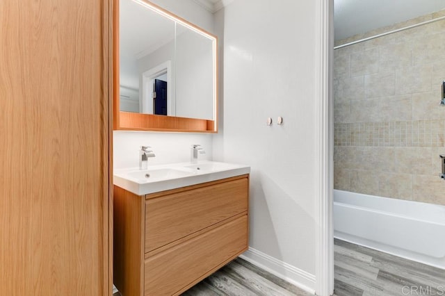 full bathroom featuring a sink, wood finished floors, double vanity, baseboards, and shower / bathtub combination