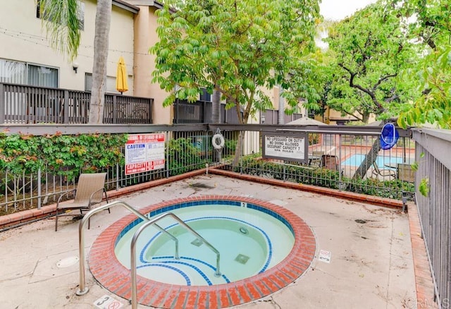 view of swimming pool featuring fence and a hot tub