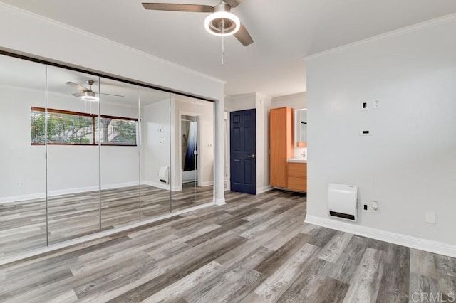 unfurnished bedroom featuring ornamental molding, ensuite bath, baseboards, and wood finished floors