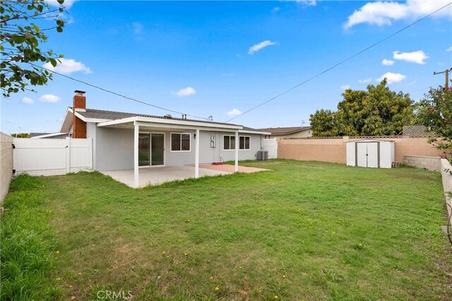 back of property with a storage unit, a lawn, a patio, a fenced backyard, and an outdoor structure