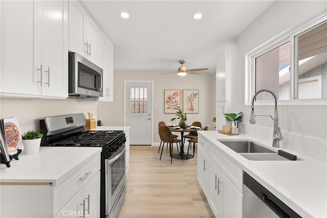 kitchen with light countertops, white cabinets, appliances with stainless steel finishes, and a sink