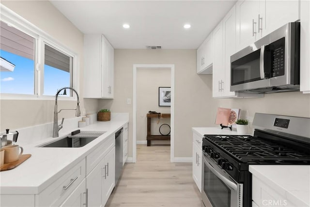 kitchen with visible vents, white cabinets, appliances with stainless steel finishes, and a sink