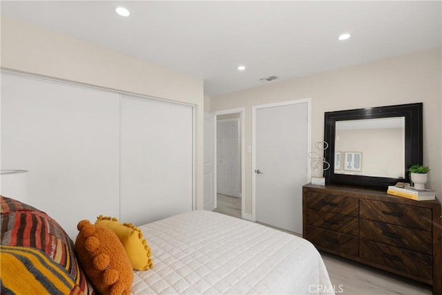 bedroom featuring visible vents, recessed lighting, light wood-style floors, and a closet