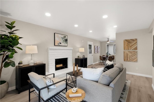 living room featuring a ceiling fan, recessed lighting, light wood-style floors, a fireplace, and baseboards