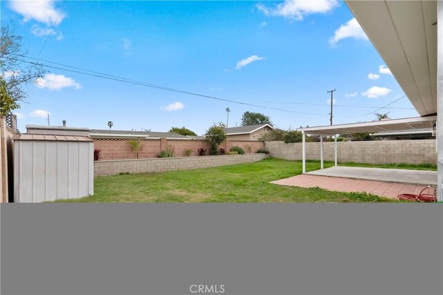 view of yard with a patio, an outbuilding, a fenced backyard, and a storage shed