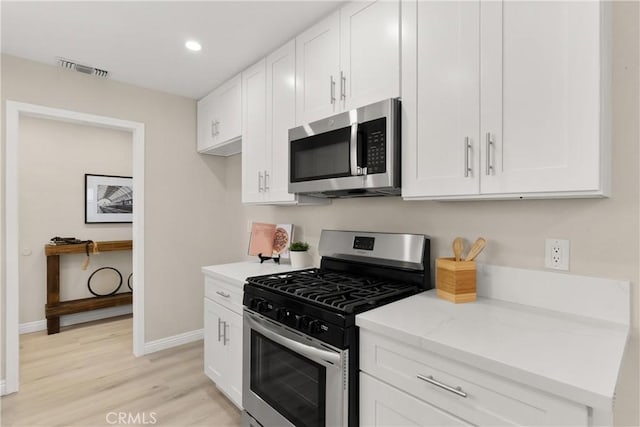 kitchen featuring white cabinetry, light wood-style floors, light stone countertops, and stainless steel appliances