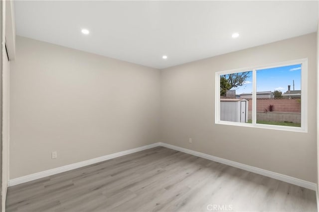 unfurnished room featuring baseboards and light wood-type flooring