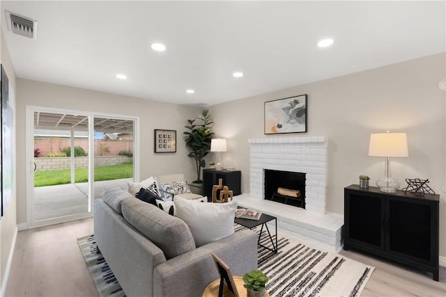 living room featuring light wood-style floors, recessed lighting, a fireplace, and visible vents