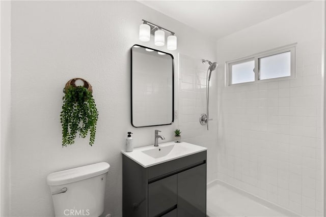 full bathroom featuring vanity, toilet, and tiled shower