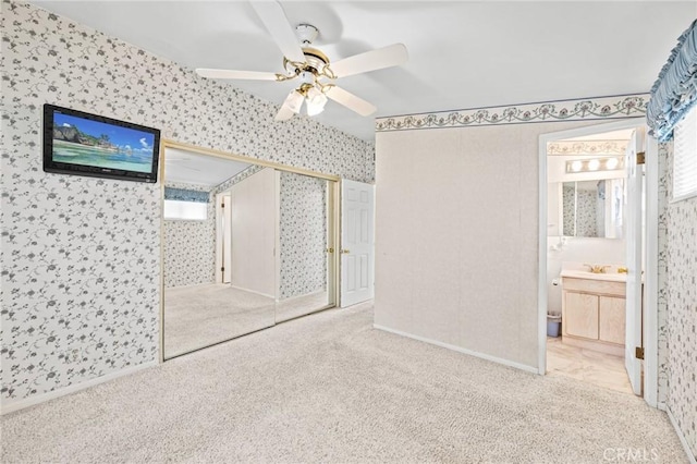 unfurnished bedroom featuring carpet floors, wallpapered walls, ceiling fan, and connected bathroom