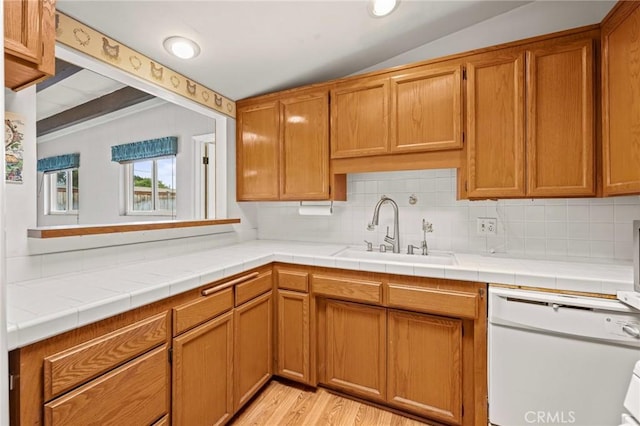 kitchen with backsplash, brown cabinetry, a sink, light wood-type flooring, and dishwasher